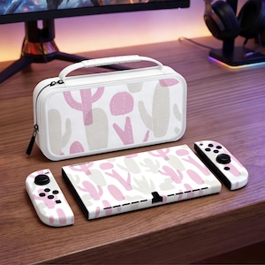 Pode incluir: Uma capa de transporte, consola e comandos Nintendo Switch brancos com um padrão de cactos rosa e cinzento. A capa tem uma pega branca e um fecho de correr preto. Os comandos têm joysticks e botões pretos.