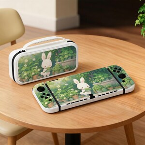 May include: A white Nintendo Switch console and carrying case featuring a garden scene with a cartoon bunny holding a plant. The case has a black zipper and handle. The console has black control buttons.