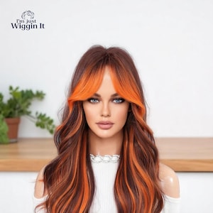 May include: A long, wavy wig with brown and orange highlights. The wig has a fringe with bright orange highlights and long, flowing strands with orange streaks. The text "I'm just Wiggin It" is in the upper left corner.