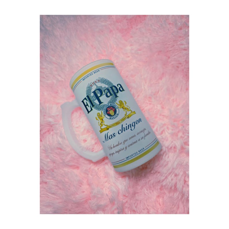 Peut inclure: Un grand mug &agrave; bi&egrave;re blanc avec le texte "El Papa" et "Mas chingon" en bleu et or. Le mug a une anse et est d&eacute;cor&eacute; d'un blason et des mots "Imported Beer".