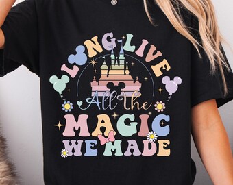 May include: Black t-shirt with a colorful graphic design featuring a castle, Mickey Mouse ears, and the text "LONG LIVE All the MAGIC WE MADE". The design includes pastel colors and floral accents.