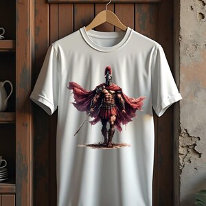 May include: White t-shirt featuring a detailed illustration of a Spartan warrior. The warrior is depicted in full armor, including a helmet and red cape, holding a sword. The design is centered on the shirt, creating a bold statement.