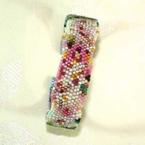 May include: A colorful beaded bracelet with a floral pattern. The bracelet is made with small, multi-colored beads and features a variety of colors, including pink, green, white, and yellow.