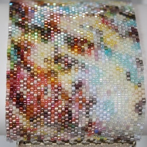 May include: A colorful beaded bracelet with a silver clasp. The beads are arranged in a swirling pattern of red, orange, yellow, green, blue, and purple.