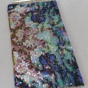 May include: A beaded bracelet with a colorful abstract pattern in shades of pink, blue, green, and purple. The bracelet is made with small, iridescent beads and has silver metal clasps.