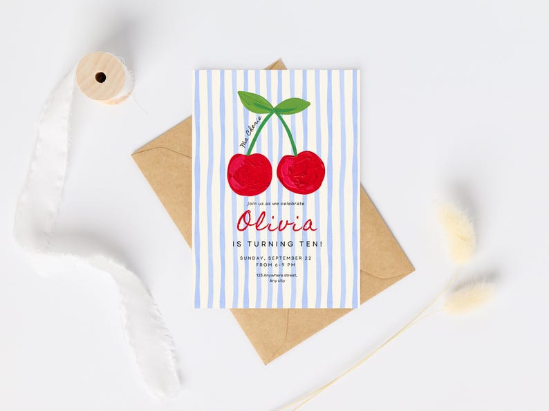 Pu&ograve; includere: Un invito di compleanno con un'illustrazione di ciliegie. La carta ha strisce blu e bianche e il testo "Olivia compie dieci anni!" L'invito &egrave; su una busta marrone.