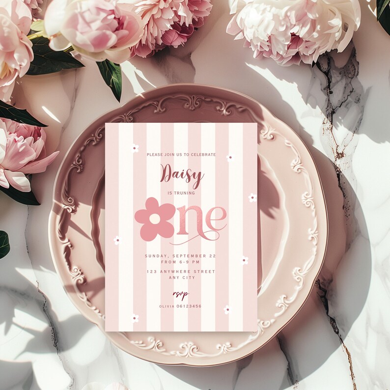 Peut inclure: Une invitation ray&eacute;e rose et blanche avec le texte "Daisy is turning one" et un motif floral. L'invitation est sur une assiette rose avec des accents floraux, entour&eacute;e de fleurs roses.