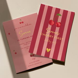 Op de afbeelding: Twee roze uitnodigingen voor een verjaardagsfeestje met kersenthema. Eén uitnodiging is roze met kersenillustraties en gouden tekst. De andere uitnodiging is rood en roze gestreept met een kersenillustratie en gouden tekst.