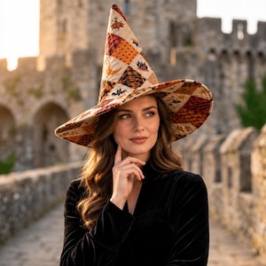 Könnte beinhalten: Ein hoher, spitzer Hexenhut mit einem gesteppten Patchwork-Design in Orange-, Braun- und Cremetönen. Der Stoff zeigt verschiedene Muster, darunter kleine Fledermäuse, Sterne und geometrische Formen, mit einer breiten, leicht geschwungenen Krempe.