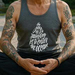 Könnte beinhalten: Eine Person in einem grauen Tanktop mit dem Text "the joy of a raindrop is to enter the ocean" meditiert im Freien. Die Person sitzt im Schneidersitz auf einem Holzdeck, umgeben von Bonsai-Bäumen und einem japanischen Garten.