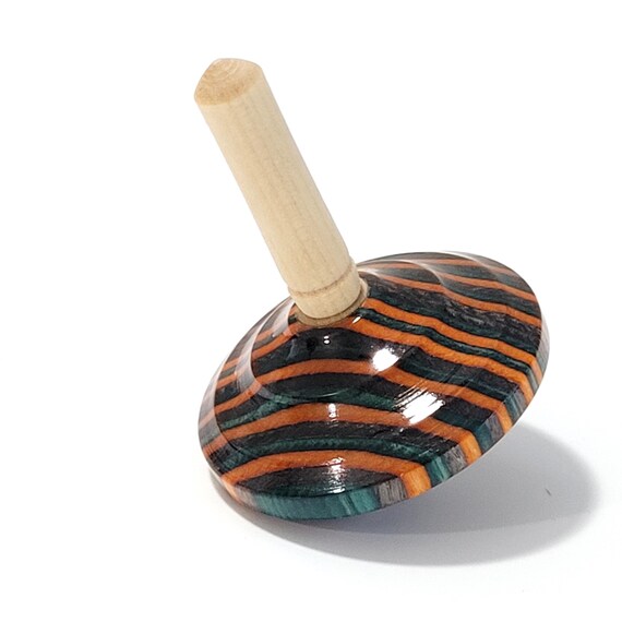A hand-turned wooden spinning top in a bold orange, teal, and gray stripe — the kind of tactile, artisan toy that looks as good on a desk as it does in a kid's hand.