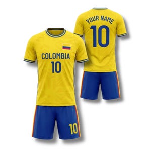 May include: A yellow soccer uniform with blue shorts. The jersey has the word "COLOMBIA" and the number "10" printed on the front. The back of the jersey has the text "YOUR NAME" and the number "10". The uniform has a Colombian flag.