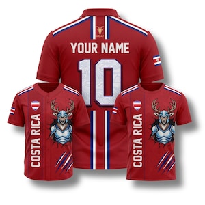 May include: Red Costa Rica soccer jerseys and t-shirts. The jerseys have white and blue accents, with the text "YOUR NAME" and the number "10" on the back. The t-shirts feature a deer graphic and the text "COSTA RICA".