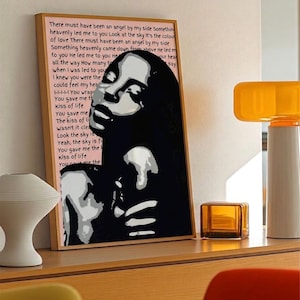 May include: A framed art print with a black and white portrait of a woman and song lyrics. The artwork has a pink background and a wooden frame. The text includes the phrase "There must have been an angel by my side."