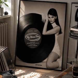 May include: A framed black and white poster featuring a person posing with a large vinyl record. The record label displays the text My House Tour, Sienna Spiro, and tour dates for Barcelona and Madrid. The Live Nation logo is at the bottom.