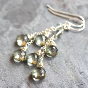 May include: Silver dangle earrings with multiple faceted green gemstone drops.