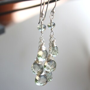 May include: Silver dangle earrings with multiple light green gemstone drops.