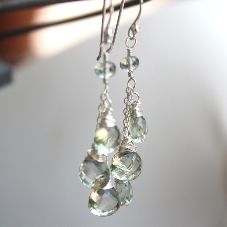 May include: Silver dangle earrings with multiple light green gemstone drops.