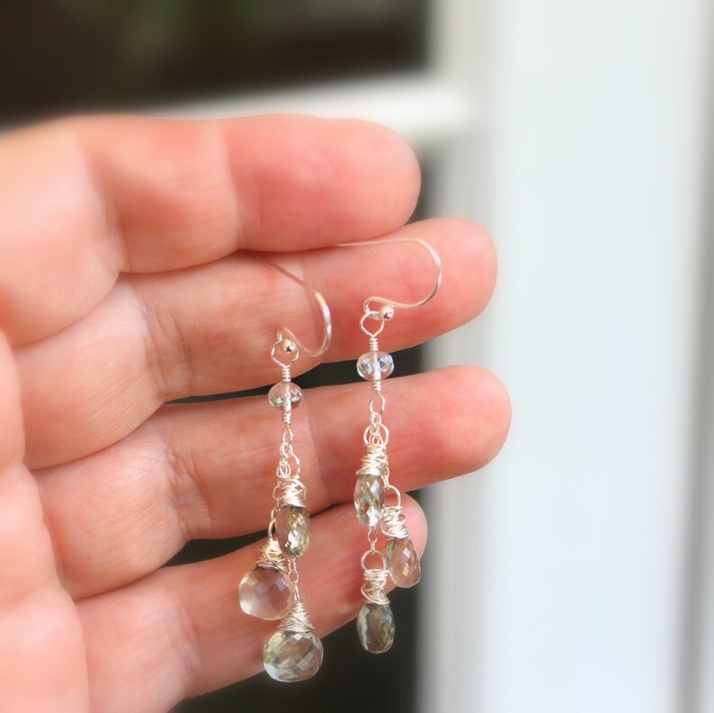 May include: Silver dangle earrings with multiple teardrop-shaped green gemstones and clear beads.