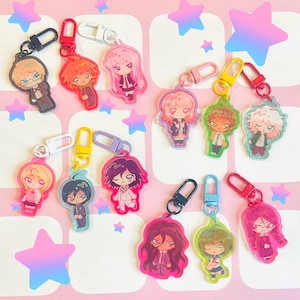 Puede incluir: Una colección de doce llaveros de acrílico con personajes de anime estilo chibi con varios colores de cabello y atuendos. Cada dije está sujeto a un broche de langosta de plástico de colores, incluyendo negro, rojo, blanco, rosa, amarillo, morado y azul.