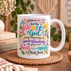 May include: A white ceramic mug featuring a colourful graphic design with the text Philippians 4:7 And the Peace of God which transcends all understanding will guard your hearts and your minds in Christ Jesus, surrounded by floral and heart motifs.