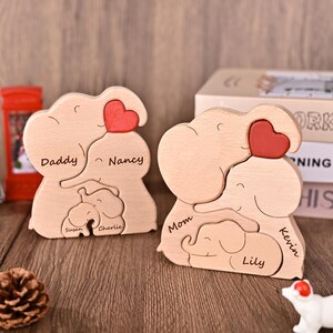 Puede incluir: Dos rompecabezas de madera de familias de elefantes. Cada rompecabezas presenta un elefante grande con un coraz&oacute;n rojo, un elefante mediano y un elefante peque&ntilde;o. Los rompecabezas est&aacute;n personalizados con nombres como "Daddy", "Mom", "Nancy", "Kevin", "Susan", "Charlie" y "Lily".