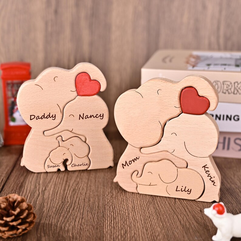 Puede incluir: Dos rompecabezas de madera de familias de elefantes. Cada rompecabezas presenta un elefante grande con un coraz&oacute;n rojo, un elefante mediano y un elefante peque&ntilde;o. Los rompecabezas est&aacute;n personalizados con nombres como "Daddy", "Mom", "Nancy", "Kevin", "Susan", "Charlie" y "Lily".