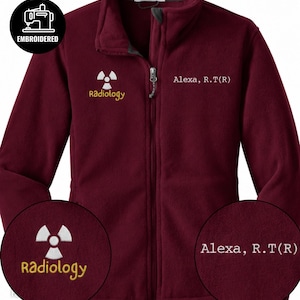 May include: A maroon fleece zip-up jacket featuring an embroidered white radiation symbol above the yellow text Radiology on the right chest and the white embroidered text Alexa, R.T(R) on the left chest, with a full-length front zipper.