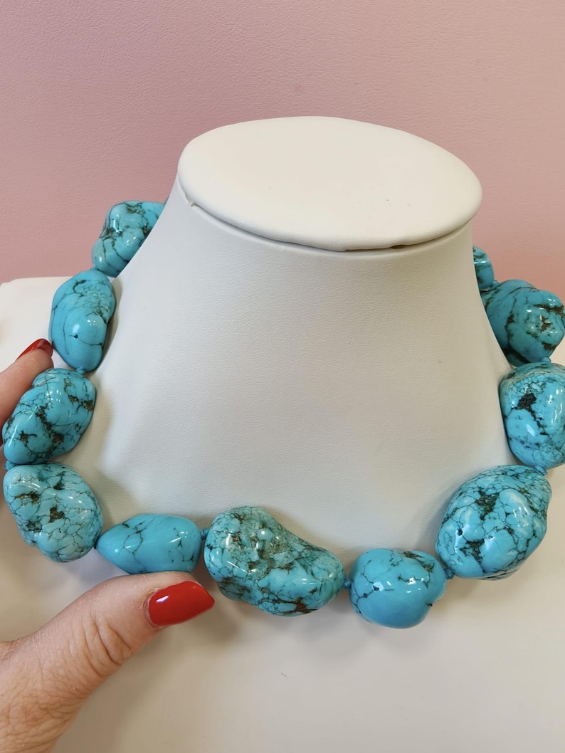 Puede incluir: Un collar compuesto por grandes piedras de turquesa pulidas e irregulares que presentan vetas de matriz de color marr&oacute;n oscuro. Las vibrantes piedras de color azul verdoso est&aacute;n ensartadas en una sola hebra, creando una pieza de joyer&iacute;a llamativa.