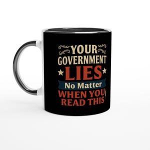 Puede incluir: Taza de cerámica en blanco y negro con interior y asa negros. La taza presenta el texto "YOUR GOVERNMENT LIES No Matter WHEN YOU READ THIS" en una fuente de estilo vintage con detalles en rojo, azul y dorado.