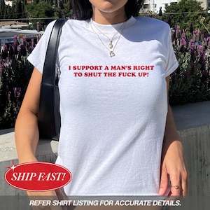 Puede incluir: Camiseta blanca con el texto rojo "I SUPPORT A MAN'S RIGHT TO SHUT THE FUCK UP!". La camiseta la lleva una persona. Se ve un bolso negro sobre el hombro. El texto "REFER SHIRT LISTING FOR ACCURATE DETAILS." está en la parte inferior.