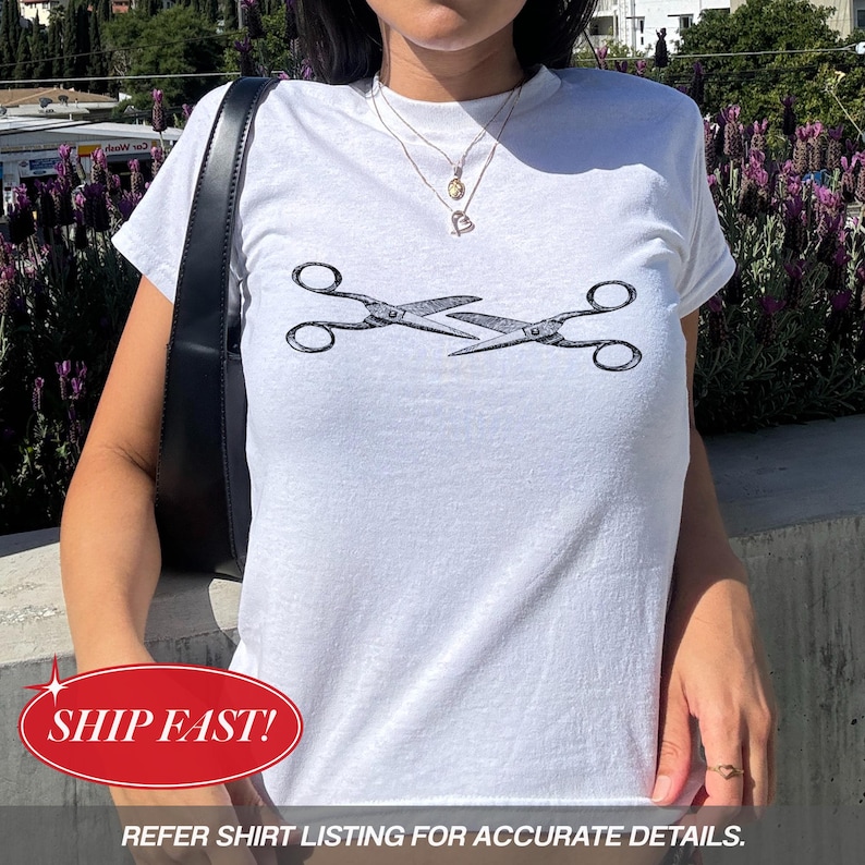 May include: White t-shirt with a black and grey scissors design. The top has a crew neck and short sleeves. The text at the bottom of the image says, "REFER SHIRT LISTING FOR ACCURATE DETAILS."