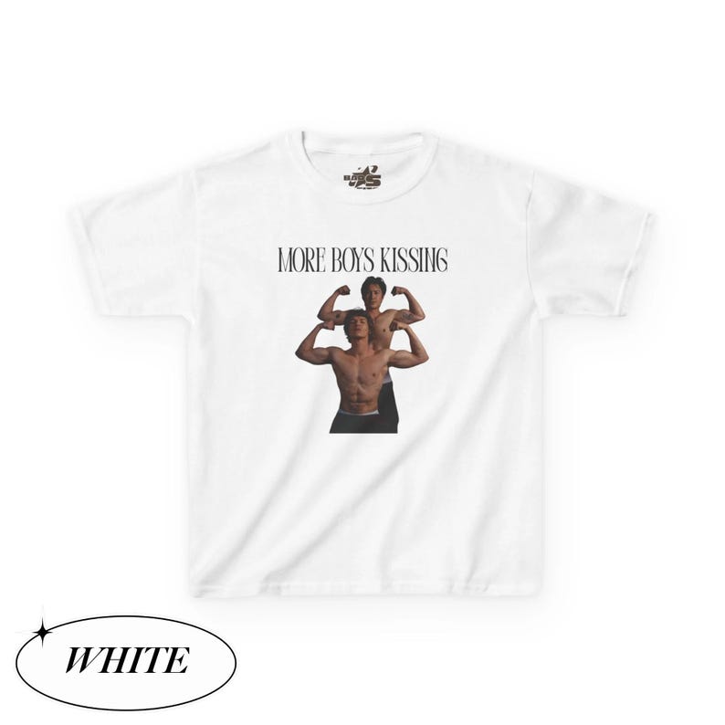 May include: White t-shirt with the text "MORE BOYS KISSING" above an image of two shirtless men flexing their muscles. The word "WHITE" is in a black oval at the bottom of the shirt.