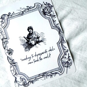May include: A white card with a black ornate border and a central illustration of a person reading. The card features the quote, "reading to disassociate while men torch the world."