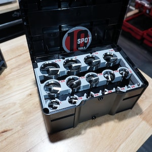 以下が含まれることがあります： 10 SPOT TOOLSと書かれた円形のロゴが付いた蓋が開いている黒いプラスチック製の工具箱。内部にはグレーのインサートがあり、それぞれ直径がラベル付けされた様々なサイズの金属製ホールソーが10個収納されています。