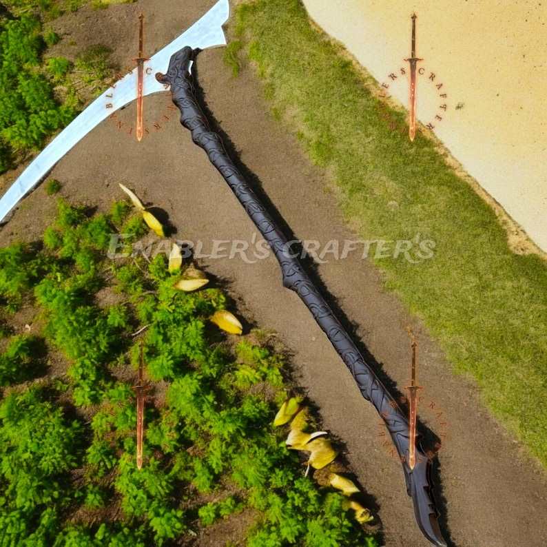 May include: A black scythe with a curved, silver blade and a dark handle with carved details. The text "ENABLER'S CRAFTER'S" is visible. The scythe is placed on a brown surface with green foliage.