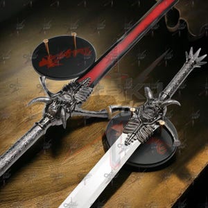 Może przedstawiać: Ozdobny miecz ze srebrną rękojeścią i czerwono-czarnym ostrzem. Rękojeść ma szczegółowy wzór z rogami i czaszką. Miecz jest prezentowany na czarnym stojaku z czerwonymi akcentami.