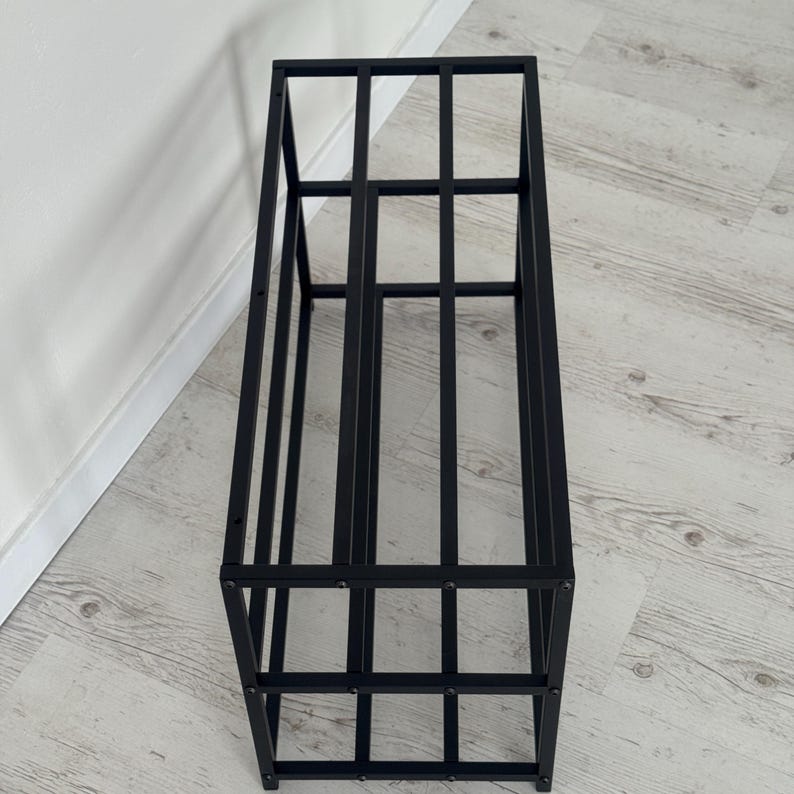 Op de afbeelding: Zwart metalen opbergrek met een rechthoekig frame en verticale en horizontale staven. Het open ontwerp maakt gemakkelijke toegang en weergave van items mogelijk. Geschikt voor diverse opslagbehoeften.