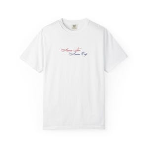 May include: A white short-sleeve t-shirt featuring a crew neckline and a small graphic centered on the chest. The graphic displays the text "America First" in a red cursive font above the text "America Only" in a blue cursive font.