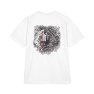 May include: White t-shirt featuring a graphic design with angel and devil wings, and the words "LOVE" and "HATE" in red. The design is set against a cloudy, dark background. The shirt has short sleeves and a crew neck.