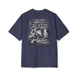 Peut inclure: T-shirt bleu marine avec un motif noir et blanc d'une voiture de course et de deux pilotes. Le motif comprend le texte "NASCAR" et "2001 Champion". Le t-shirt est à col rond et à manches courtes.