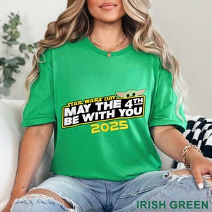 Puede incluir: Una camiseta verde con el texto "STAR WARS DAY MAY THE 4TH BE WITH YOU 2025" en amarillo y blanco. El dise&ntilde;o incluye una imagen de dibujos animados de Grogu. La camiseta es "IRISH GREEN".