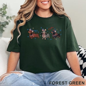 May include: Forest green t-shirt featuring three dachshunds with patriotic bow ties and surrounded by blue stars. The text "FOREST GREEN" is printed at the bottom of the shirt. The shirt is a comfortable, casual style.