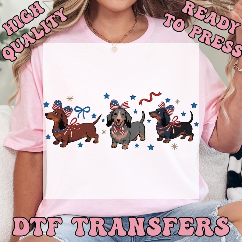 May include: DTF transfers featuring three dachshunds with patriotic bows and ribbons, surrounded by stars. The text "HIGH QUALITY READY TO PRESS DTF TRANSFERS" is displayed in a pink, retro font.