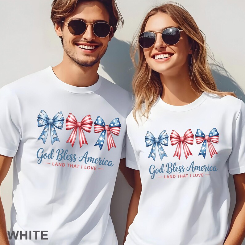 May include: White t-shirts with a patriotic design. The shirts feature three bow illustrations in red, white, and blue, with the text "God Bless America - Land That I Love." The word "WHITE" is at the bottom of the image.