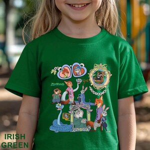 May include: Irish green t-shirt featuring a colorful graphic of characters from the movie Zootopia. The design includes framed portraits and various animal characters. The word "Zootopia" is printed in green. The shirt is made of a soft material.