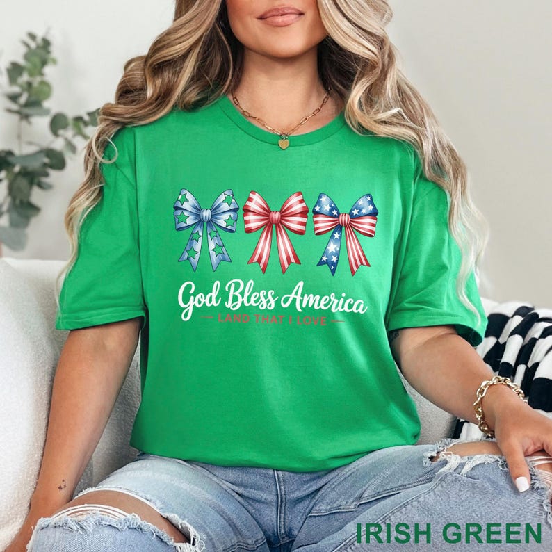 May include: A green t-shirt with the text "God Bless America" and three bow designs in red, white, and blue. The bows have star and stripe patterns. The shirt is labeled "Irish Green" at the bottom.