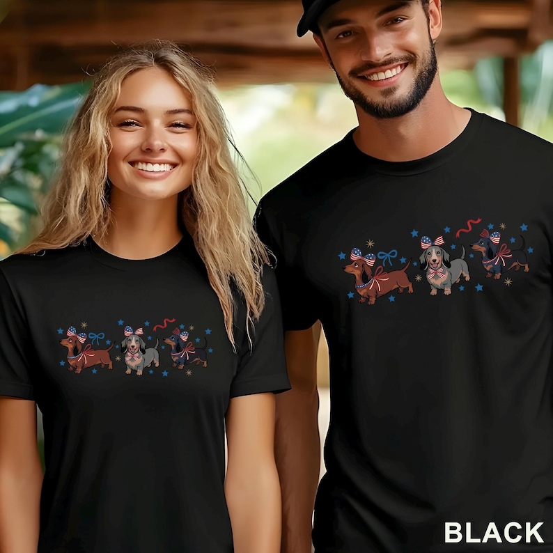 May include: Black t-shirts featuring a dachshund dog design with patriotic bows and stars. The shirts are worn by two people. The word "BLACK" is printed in white at the bottom right corner.