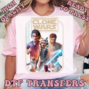 May include: White t-shirt featuring a graphic from Star Wars: The Clone Wars. The design includes characters like Anakin Skywalker, Ahsoka Tano, and Obi-Wan Kenobi, with the text "STAR WARS THE CLONE WARS". The words "HIGH QUALITY READY TO PRESS DTF TRANSFERS" are also visible.