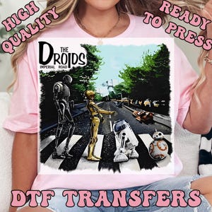 May include: A DTF transfer featuring a parody of the Beatles' Abbey Road album cover, with Star Wars droids crossing a crosswalk. The text reads "The Droids Imperial Road". The image is labeled "High Quality" and "Ready to Press".